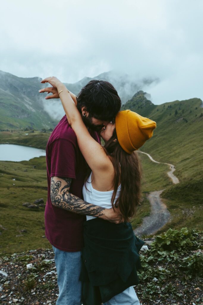 A couple holds each other during their couples session in Switzerland. Thie girl holds her arms around her boyfriend's neck as he has his hands on her waist and is leaning in to kiss