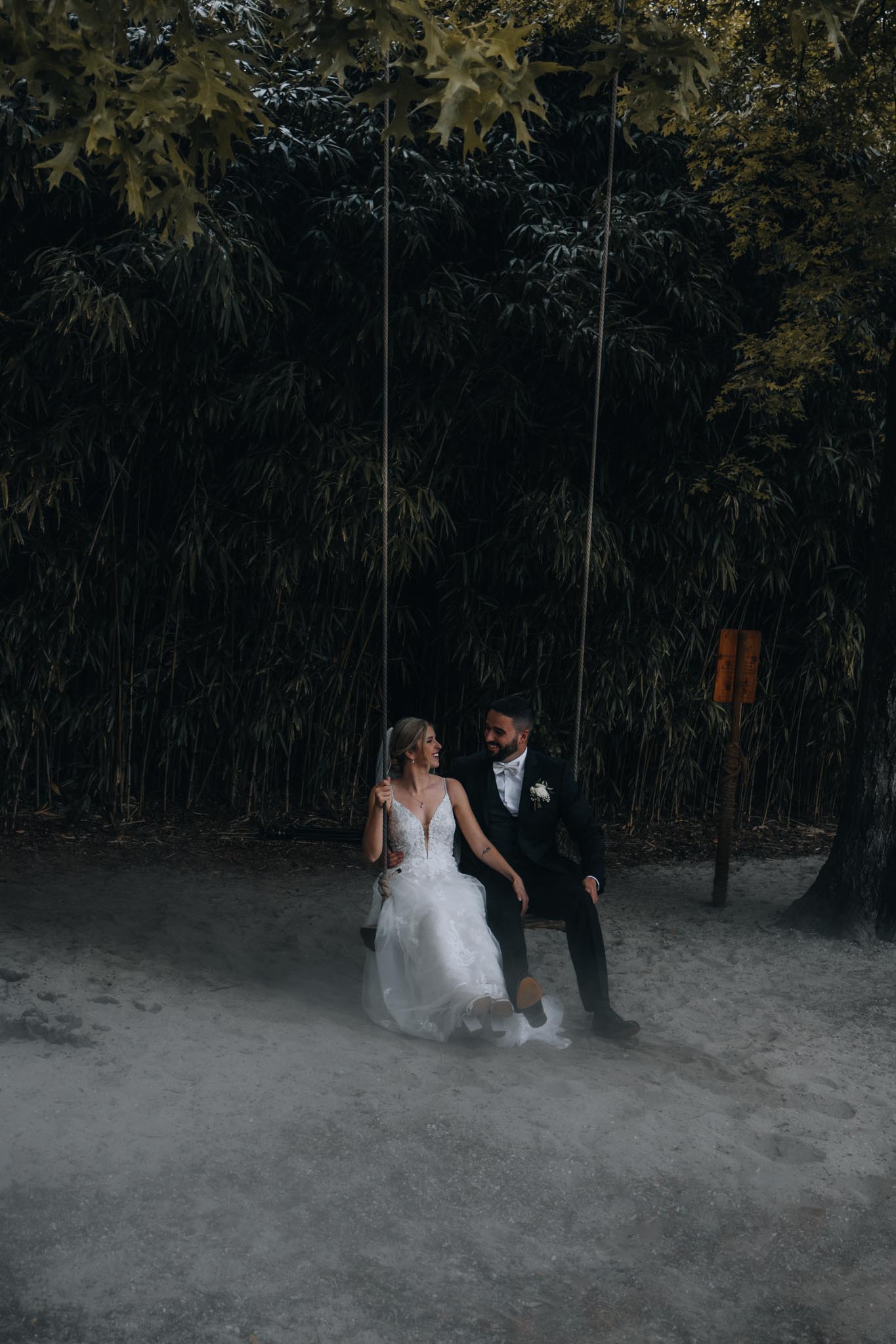 A married couple sits on a swing in the forest after their wedding in the Brissago Islands, Switzerland