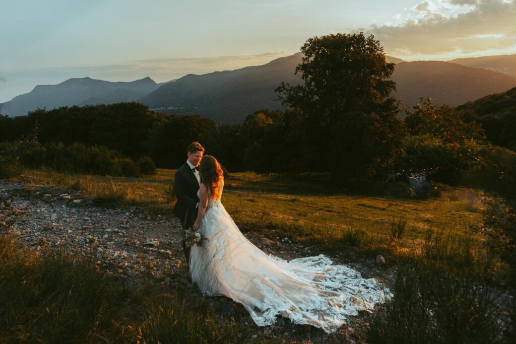 During their elopement in the Swiss Alps, a couple stands together in a meadow during golden hour, holding each other