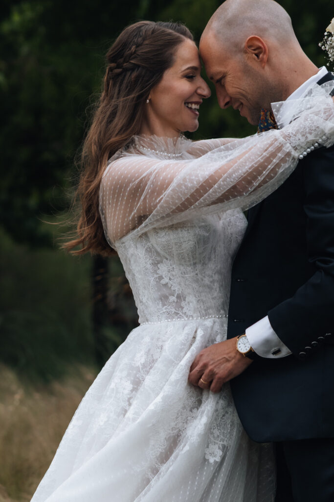 During their elopement in Switzerland, a bride and groom look at each other smiling while touching foreheads. The bride's arms are around the groom's neck in a tight embrace, while she holds her bouquet in her hand