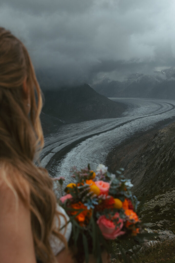 A bride looks at a glacier in the distance during her glacier elopement in Switzerland