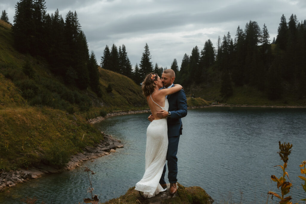A couple embraces in front of a swiss mountain lake during their elopement in Switzerland