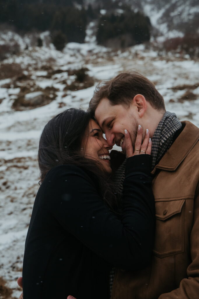 Close up of a couple, the woman holds the mans face gently and smiles