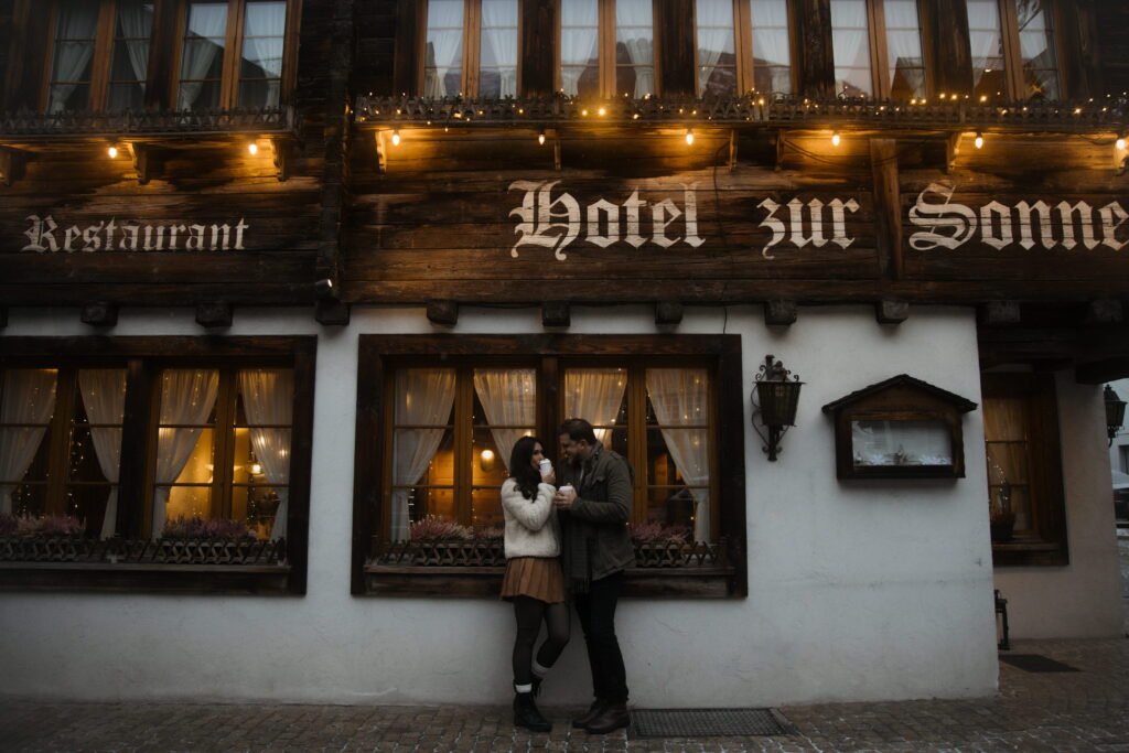 Couple spis coffee in front of a hotel in the evening in Andermatt